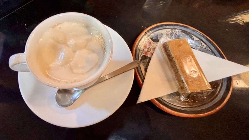 可否館のレトロなテーブルに置かれた、なめらかなクリームが乗ったウィンナ珈琲と香ばしいくるみクッキー
