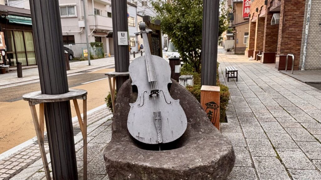 材木町のストリートに設置された、セロ弾きのゴーシュをモチーフにしたブロンズのセロのオブジェ